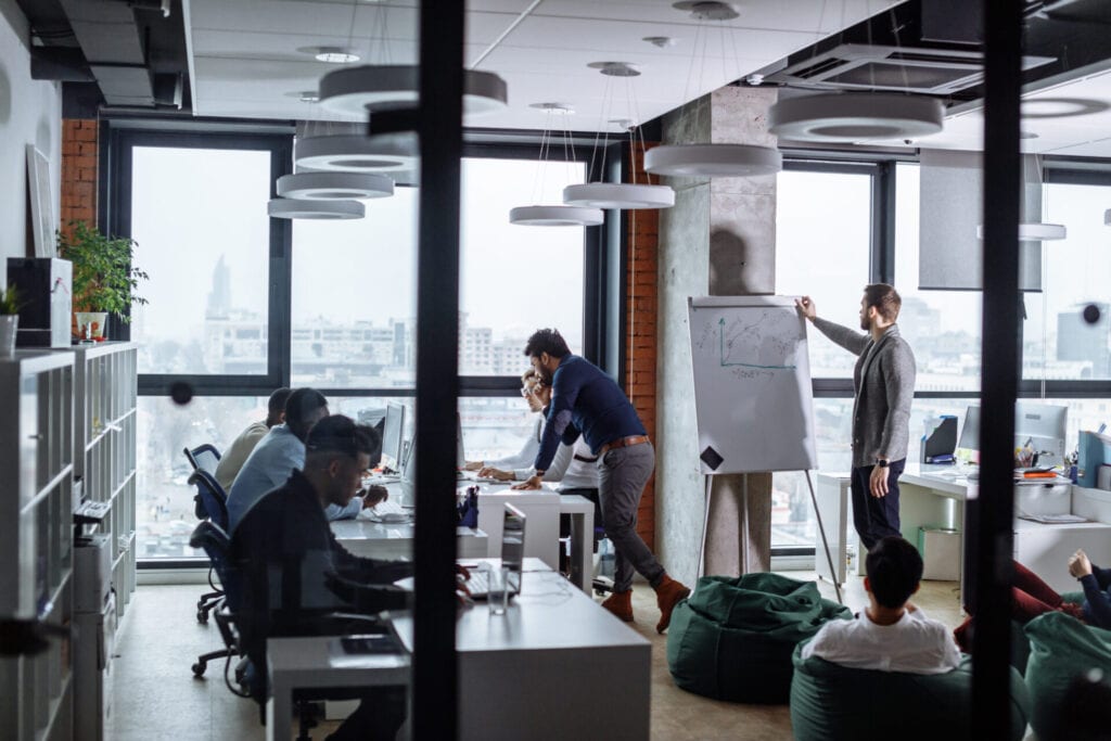 Business men in an open space office interior with a panoramic window, long shot